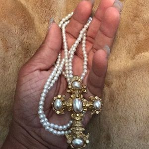 Long white pearl necklace with cross pendant.